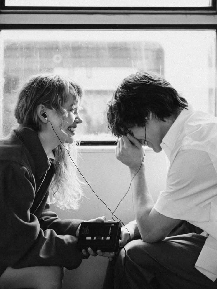 A couple laughing while sharing wired headphones